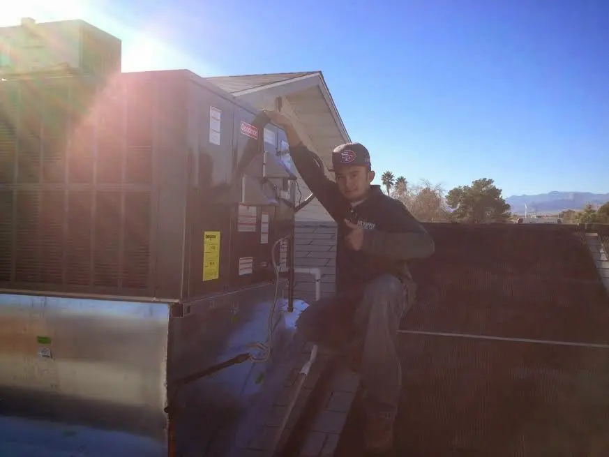 HVAC technician performing Air Duct Cleaning on a rooftop unit in Boston