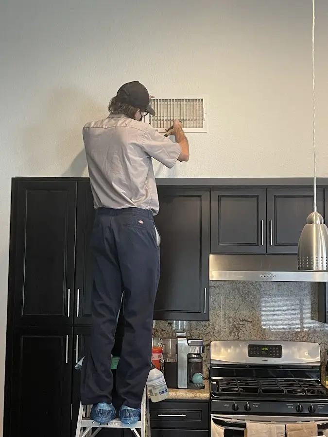 Technician inspecting an air vent during HVAC service in Boston
